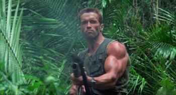 Movie still from “Predator” (1987), directed by John McTiernan – A man holding a gun in the woods; Medium shot, Low angle
