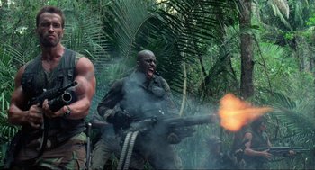 Movie still from “Predator” (1987), directed by John McTiernan – A group of men standing in the woods with guns; Medium shot, Low angle