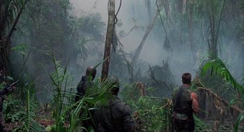 Movie still from “Predator” (1987), directed by John McTiernan – A group of men standing on top of a lush green forest; Extreme Wide shot, Low angle