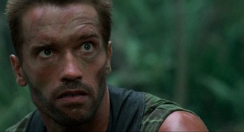 Movie still from “Predator” (1987), directed by John McTiernan – A man's face in the woods; Close Up shot, Low angle