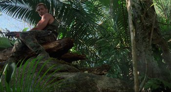 Movie still from “Predator” (1987), directed by John McTiernan – A man is climbing on a tree in the jungle; Wide shot, Low angle