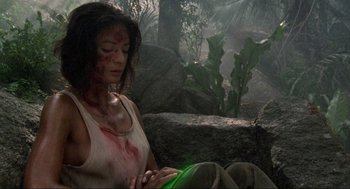 Movie still from “Predator” (1987), directed by John McTiernan – A woman in a white tank top holding a green frisbee; Medium shot, High angle