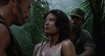 Movie still from “Predator” (1987), directed by John McTiernan – A man and a woman standing next to each other in the woods; Close Up shot, Over the shoulder angle