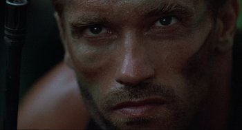 Movie still from “Predator” (1987), directed by John McTiernan – A man's face in the dark; Extreme Close Up shot, Low angle