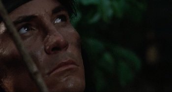 Movie still from “Predator” (1987), directed by John McTiernan – A man's face in a forest; Extreme Close Up shot, Low angle
