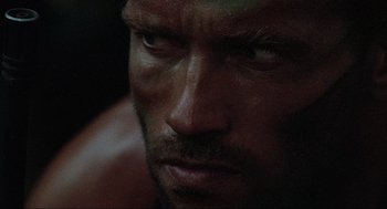 Movie still from “Predator” (1987), directed by John McTiernan – A man's face in the dark; Extreme Close Up shot, Low angle