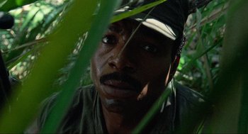 Movie still from “Predator” (1987), directed by John McTiernan – A person with a hat on; Close Up shot, Low angle