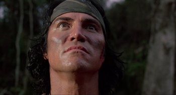 Movie still from “Predator” (1987), directed by John McTiernan – A person with a bandage on his head; Close Up shot, Low angle