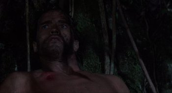 Movie still from “Predator” (1987), directed by John McTiernan – A shirtless man in the woods at night; Close Up shot, Low angle