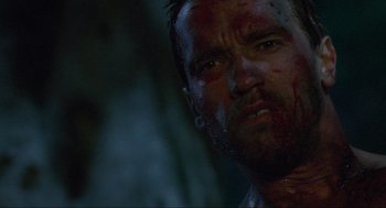 Movie still from “Predator” (1987), directed by John McTiernan – A person with blood all over his face; Close Up shot, Low angle