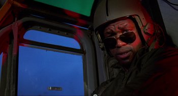 Movie still from “Predator” (1987), directed by John McTiernan – A man wearing a helmet and sunglasses in a helicopter; Close Up shot, Low angle