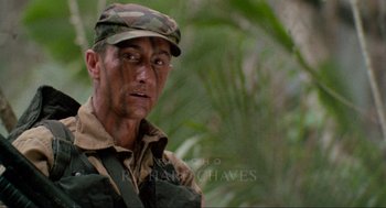 Movie still from “Predator” (1987), directed by John McTiernan – A man in a military uniform looking at the camera; Close Up shot, Low angle