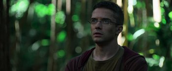 Movie still from “Predators” (2010), directed by Nimród Antal – A man with glasses is looking up in the woods; Close Up shot, Over the shoulder angle