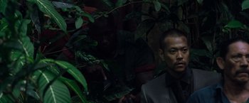 Movie still from “Predators” (2010), directed by Nimród Antal – A man in a suit and tie standing next to a tree; Close Up shot, Over the shoulder angle