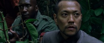 Movie still from “Predators” (2010), directed by Nimród Antal – A man with a beard is looking into the camera; Close Up shot, Low angle
