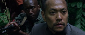 Movie still from “Predators” (2010), directed by Nimród Antal – Two men are posing for a picture in the woods; Close Up shot, Low angle