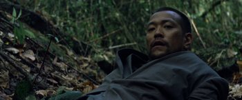 Movie still from “Predators” (2010), directed by Nimród Antal – A person laying on the ground in the woods; Close Up shot, High angle