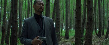Movie still from “Predators” (2010), directed by Nimród Antal – A man holding a gun while standing in the woods; Medium shot, Low angle