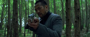 Movie still from “Predators” (2010), directed by Nimród Antal – A man holding a gun while standing in the woods; Close Up shot, Low angle