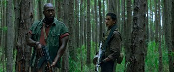 Movie still from “Predators” (2010), directed by Nimród Antal – Two men standing next to each other in the woods; Medium shot, Low angle