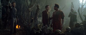 Movie still from “Predators” (2010), directed by Nimród Antal – Two men talking in a forest with a skeleton; Medium shot, Over the shoulder angle