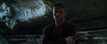 Movie still from “Predators” (2010), directed by Nimród Antal – A man standing in front of a cave with his arms crossed; Close Up shot, Low angle