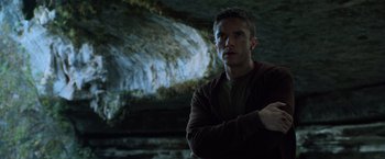 Movie still from “Predators” (2010), directed by Nimród Antal – A man standing in front of a cave with his arms crossed; Close Up shot, Low angle