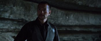 Movie still from “Predators” (2010), directed by Nimród Antal – A man in a black vest and a black shirt; Close Up shot, Low angle