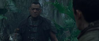 Movie still from “Predators” (2010), directed by Nimród Antal – A man standing in the middle of a forest; Medium shot, Low angle