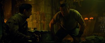 Movie still from “Predators” (2010), directed by Nimród Antal – A man standing in front of a table with a knife; Medium shot, Low angle