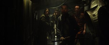 Movie still from “Predators” (2010), directed by Nimród Antal – A group of people standing in a dark room; Medium shot, Low angle