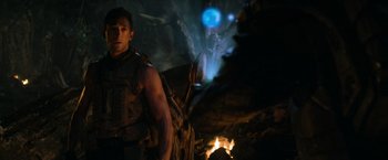 Movie still from “Predators” (2010), directed by Nimród Antal – A man standing next to a fire in a cave; Medium shot, Over the shoulder angle