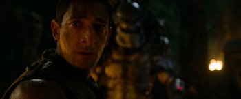 Movie still from “Predators” (2010), directed by Nimród Antal – A man's face in the dark; Close Up shot, Over the shoulder angle