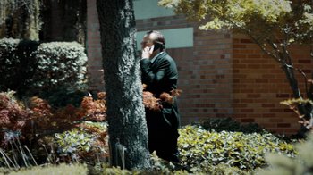 Movie still from “Pride Jewel” (2022), directed by Doug Thomsen – A man is talking on a cell phone while walking by a tree; Medium shot, Low angle