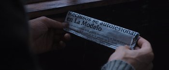 Movie still from “Prison 77” (2022), directed by Alberto Rodríguez – A person is holding a newspaper in their hand; Extreme Close Up shot, Overhead angle