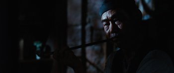 Movie still from “Australia” (2008), directed by Baz Luhrmann – A man holding a wooden stick in a dark room; Close Up shot, Low angle