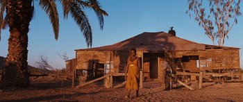 Movie still from “Australia” (2008), directed by Baz Luhrmann – A person standing in front of a wooden house; Extreme Wide shot, Low angle