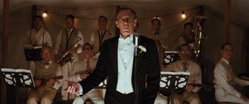 Movie still from “Australia” (2008), directed by Baz Luhrmann – An older man in a tuxedo is singing; Medium shot, Low angle