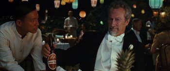 Movie still from “Australia” (2008), directed by Baz Luhrmann – An older man in a tuxedo holding a bottle of beer; Medium shot, Low angle