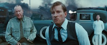 Movie still from “Australia” (2008), directed by Baz Luhrmann – A man in a suit and tie in front of a car; Close Up shot, Low angle