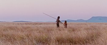 Movie still from “Australia” (2008), directed by Baz Luhrmann – Two people in a grassy field with a spear in their hand; Extreme Wide shot, Over the shoulder angle