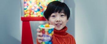 Movie still from “Prisoners of the Ghostland” (2021), directed by Sion Sono – A young boy holding a cup of jelly beans; Close Up shot, Over the shoulder angle