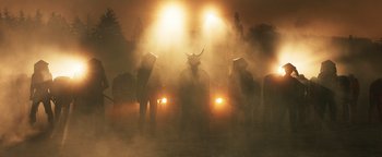 Movie still from “Prisoners of the Ghostland” (2021), directed by Sion Sono – A group of people standing in a field at night; Extreme Wide shot, Low angle