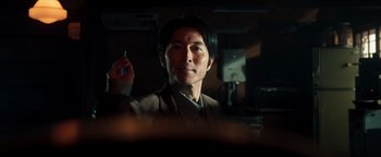 Movie still from “Prisoners of the Ghostland” (2021), directed by Sion Sono – A man holding a pen in his other hand; Close Up shot, Low angle