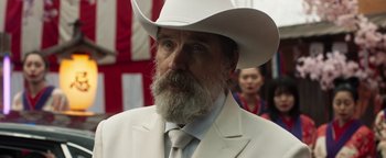 Movie still from “Prisoners of the Ghostland” (2021), directed by Sion Sono – A man in a white suit and a white cowboy hat; Close Up shot, Over the shoulder angle