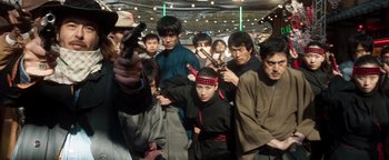 Movie still from “Prisoners of the Ghostland” (2021), directed by Sion Sono – A group of people standing around each other; Medium shot, High angle