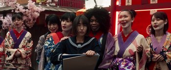 Movie still from “Prisoners of the Ghostland” (2021), directed by Sion Sono – A group of women standing around each other holding a laptop; Medium shot, Low angle