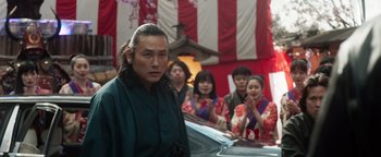 Movie still from “Prisoners of the Ghostland” (2021), directed by Sion Sono – A group of people standing in front of a building; Medium shot, Low angle