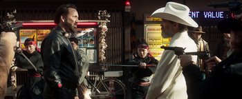 Movie still from “Prisoners of the Ghostland” (2021), directed by Sion Sono – A man in a cowboy hat is talking to a man in a cowboy hat; Medium shot, Over the shoulder angle