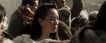 Movie still from “Prisoners of the Ghostland” (2021), directed by Sion Sono – A young woman is standing among a group of people; Close Up shot, High angle